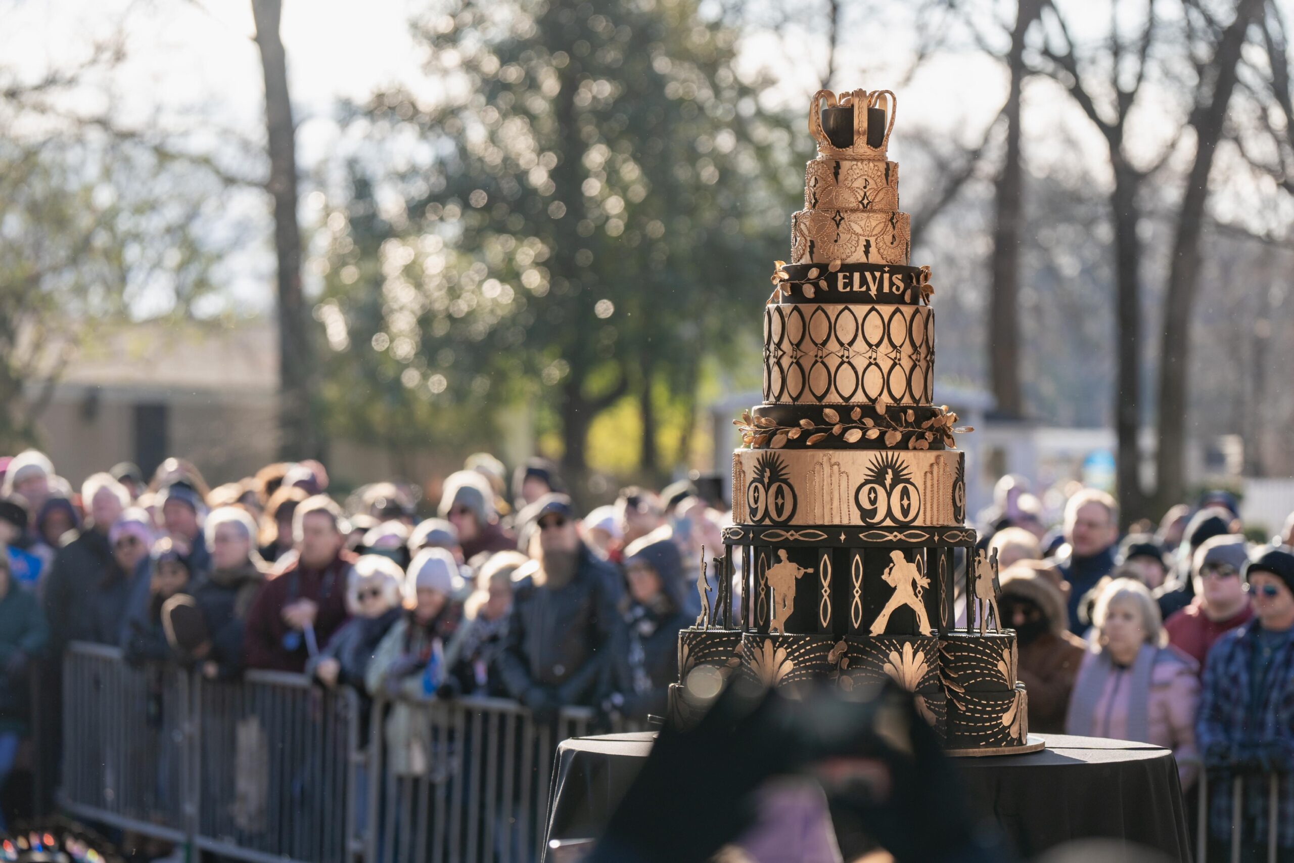A large group of spectators gathering around the birthday cake at Elvis' Birthday Celebration at Graceland.
