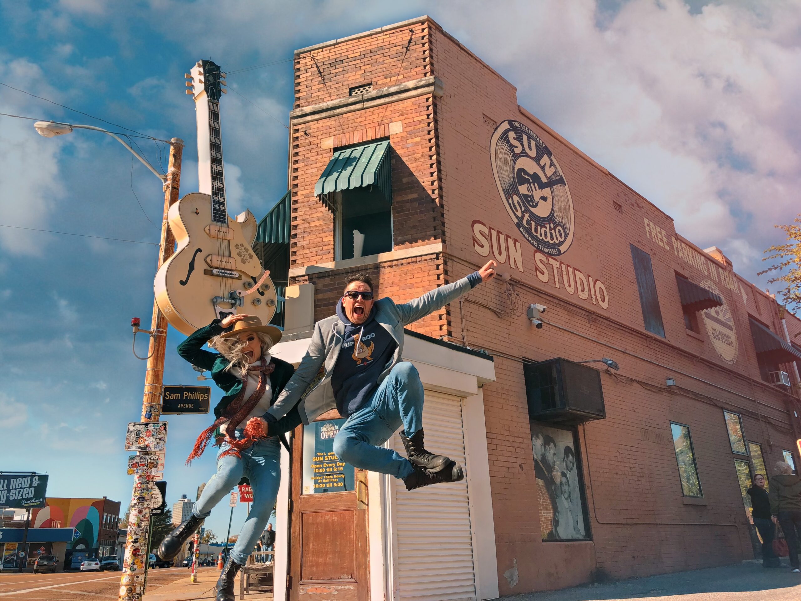 Two visitors pose by jumping in front of Memphis' Sun Studio