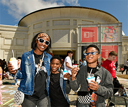 A family stands together smiling on the plaza of the Memphis Brooks Museum of Art during a community event