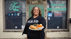 An employee stands outside of Memphis' Four Way Grill with a platter of catfish and vegetables