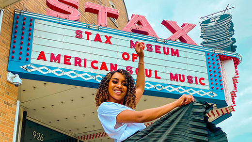 A woman posing beneath the Stax Museum of American Soul Music sign. 