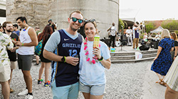 A couple posing in front of the band and a crowd at Taste the Rarity at Wiseacre Brewing Company.