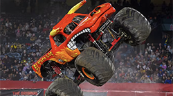 A monster truck performing stunts in front of a crowd. 