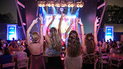 Concertgoers facing the stage with their arms raised at Radians Amphitheater.