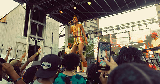 A performer on stage in front of a crowd at TONE's Juneteenth: A Family Reunion Weekend.