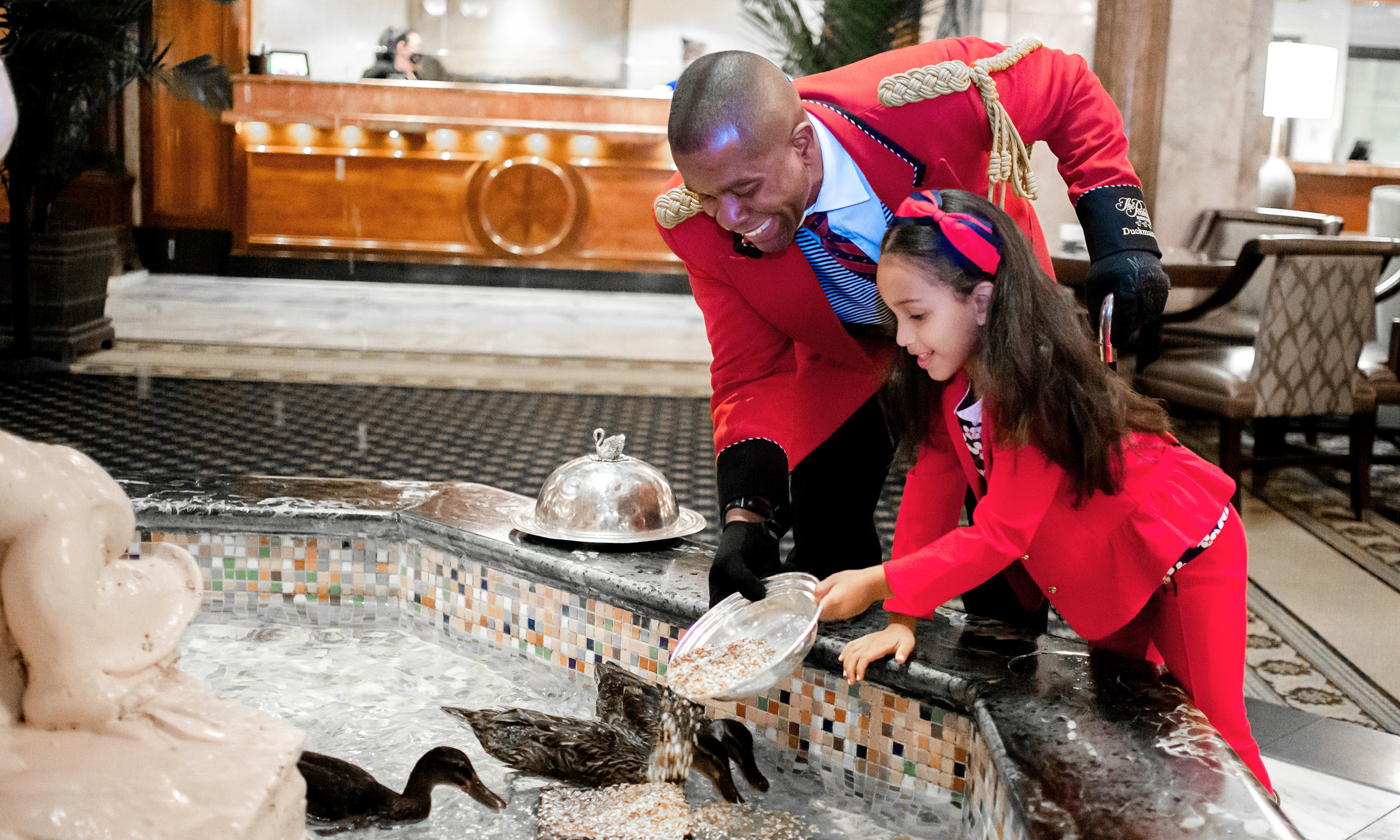 The Duckmaster helping a child feed the ducks inside the lobby pond at The Peabody Hotel.