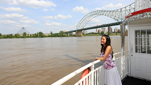 A woman enjoying views of the Mississippi River and downtown Memphis skyline on a Memphis Riverboat cruise