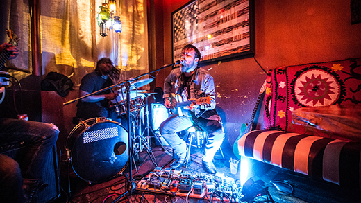 A performer strums a guitar while singing into a microphone at the cozy Bar DKDC in Cooper-Young.