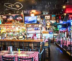 The interior of one of Huey's Restaurants, featuring warm lighting, quirky decor and red-and-white checkered tablecloths.