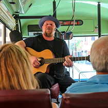 A singing tour guide entertains an audience during a bus ride through Memphis.