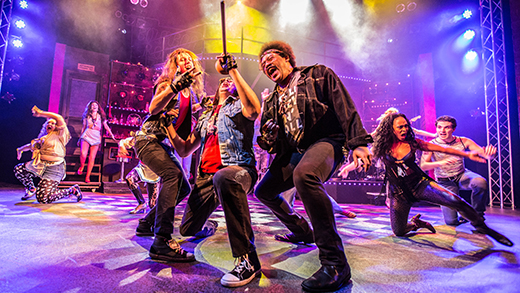 Performers on stage at Playhouse on the Square, singing dressed as rock and rollers.