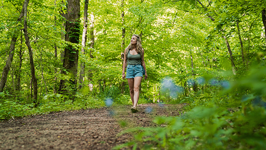 A woman walking the trails surrounded by green foliage at Meeman-Shelby Forest State Park.