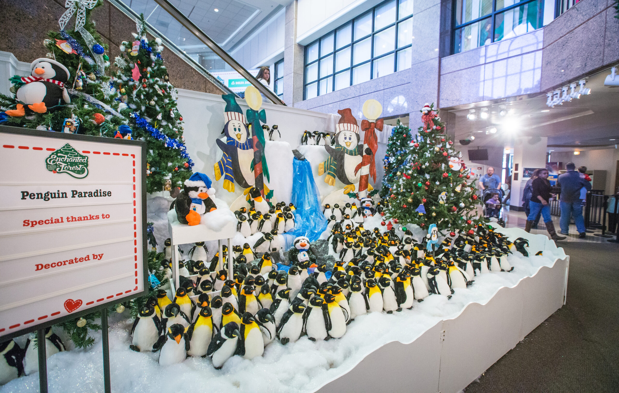 Penguin Paradise display with penguins among Christmas trees at The Enchanted Forest Festival of Trees at Pink Palace Museum & Mansion.