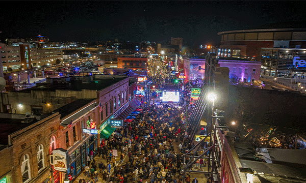 A rotating series of images showing an aerial view of a massive crowd of people celebrating New Year's on Beale Street, a group performing on stage at B.B. King's Blues Club on Beale, and a shot of confetti falling over a crowd during the New Year's Eve celebration on Beale Street. 