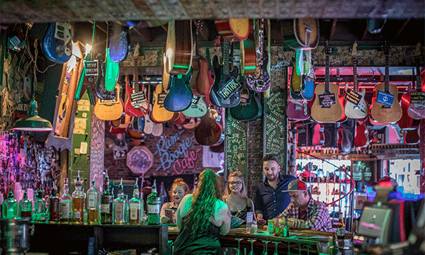A rotating series of images showing a group of people sitting beneath the hanging guitars at the bar of Rum Boogie Cafe on Beale Street, a waiter showing off plates of barbecue at world-famous Rendezvous, and kids dressed up like firefighters at the Fire Museum of Memphis.