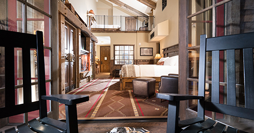 View inside a room with rustic styles from the balcony, shot between two rocking chairs. 