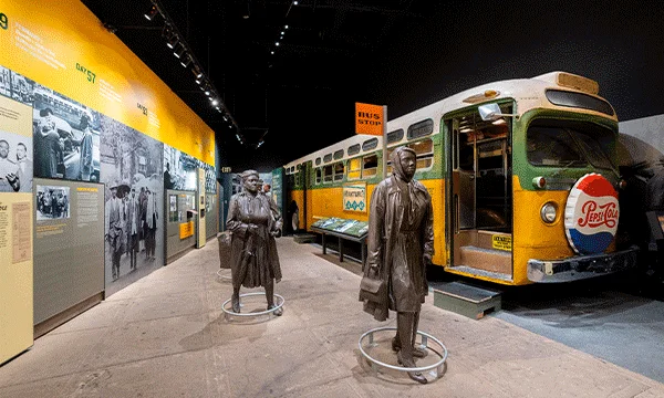 A rotating series of images showing an exhibit of the Montgomery Bus Boycott at the National Civil Rights Museum featuring a bus and statues, a tour guide speaking to guests in front of photos at the Withers Collection Museum & Gallery, and the owner of Alcenia's posing with a plate of soul food inside the restaurant. 