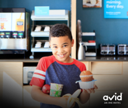 A child carrying cereal, an apple, a banana and a muffin at the breakfast area at avid Hotel Memphis Southaven.