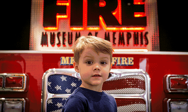 A rotating series of images showing a child in front of a fire truck at the Fire Museum of Memphis, a girl beneath a giraffe at the giraffe feeding exhibit at Memphis Zoo and family looking at the fossils of a mastodon at Pink Palace Museum & Mansion.  