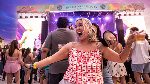 A woman dancing with a crowd behind her gathered at a large stage at RiverBeat Music Fest.