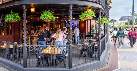 People on the ground-level patio at Lafayette's Music Room, with a tv and bar on-site. 