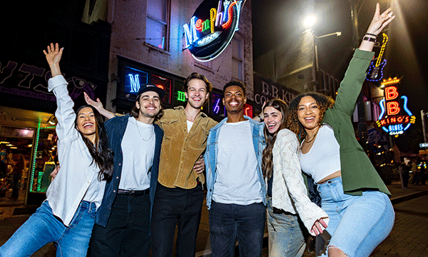 A rotating series of images showing a group of friends under the neon signs of Beale Street, a crowd in lawn chairs at a Live at the Garden concert at Radians Amphitheater, and actors portraying Beauty and the Beast dance on stage in Disney's Beauty and the Beast.
