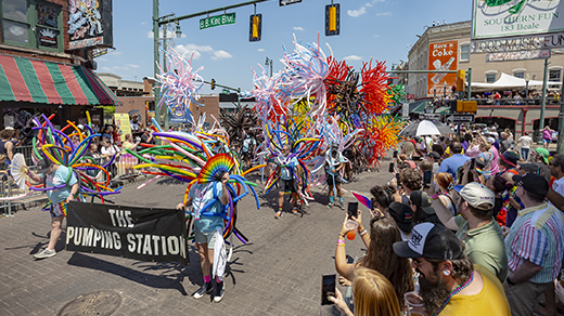 Marchers with colorful balloon accessories walk down Beale Street during the Memphis Pride Parade.