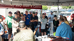 A crowd watches pitmasters at work in a booth at the World Championship Barbecue Cooking Contest.