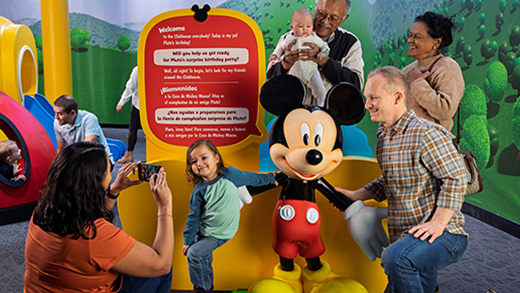 Families pose for pictures with Mickey Mouse in Mickey Mouse Clubhouse: The Exhibit