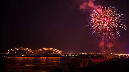 Fireworks light up the sky next to the lit up Hernando de Soto Bridge over the Mississippi River.