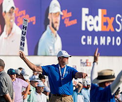 Volunteer holds up “HUSH YALL” sign at FedEx St. Jude Championship.