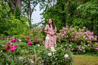 A woman admiring blooming peonies in a garden.