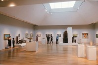 People examining paintings displayed in an art museum. 