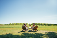 Two woman sitting in a vineyard with wine glasses.