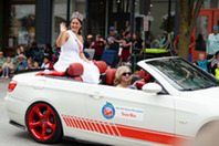 A woman waving from a convertible car in a parade.