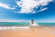 A woman running in the water on a beach.