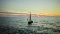 A sail boat on the great lakes at sunset.