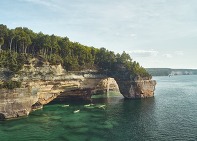 Kayakers paddling below the Lovers Leap arch over Lake Superior at Pictured Rocks. 