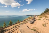 A man and woman sitting on a bench at the top of Sleeping Bear Dunes overlooking Lake Michigan.