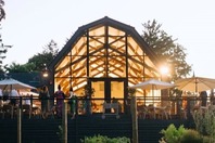 People socializing on a porch around a glass barn. 