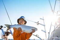 A young boy holding a salmon he caught on a charter boat. 