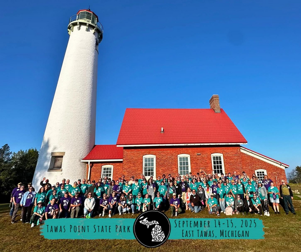A group of volunteers gathered for a photo in front of the Tawas Point Lighthouse. 
