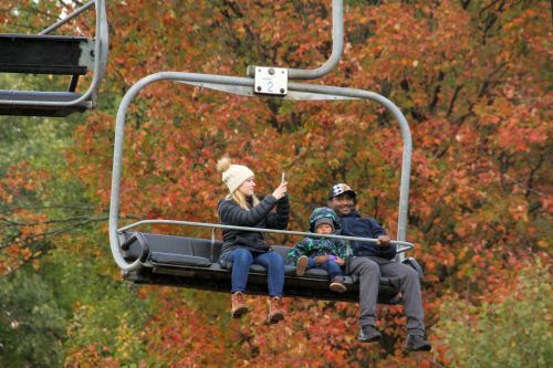 A man, woman, and child on a scenic chairlift ride during fall. 