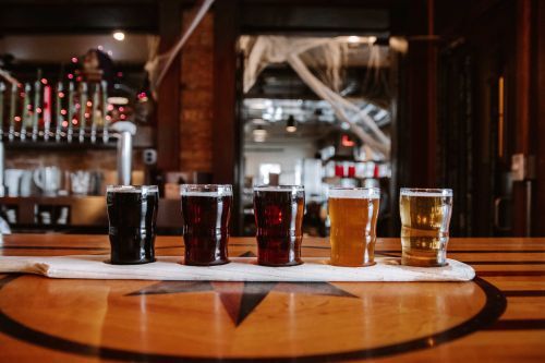 A flight of different flavors of beer on a wooden table in a brewery. 