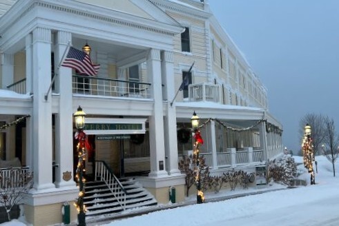The exterior of a historic hotel decorated with holiday lights and covered in snow. 