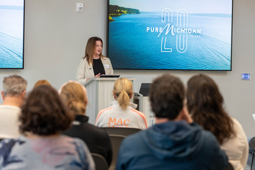 Vice President of Pure Michigan, Kelly Wolgamott, speaking at a podium during a press conference. 