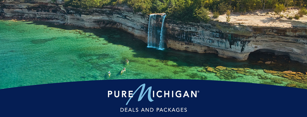 Kayakers paddling by a waterfall at Pictured Rocks National Lakeshore with overlaying text that reads "Featured Deals & Packages".