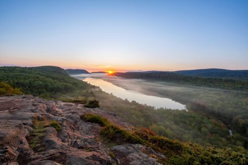 A mountain lake in a forested valley at sunrise. 