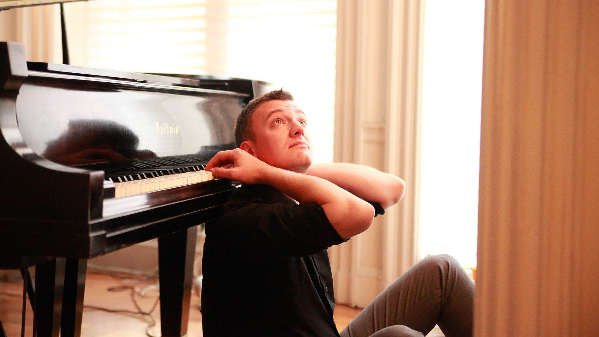 a man leaning backwards on a piano