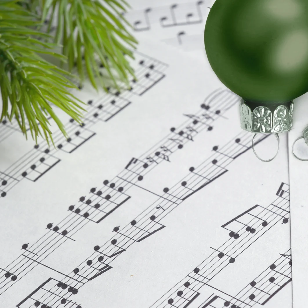 sheet music with a green ornament and pine needles framing the top